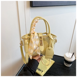 Détail du sac seau en PVC jaune crème avec poignée en foulard de soie et fermoir doré