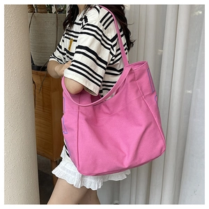 Detail shot of large rose pink canvas tote bag with blue letter print on the side