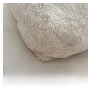 Close-up of white floral lace embroidery and fine mesh detail on the canvas tote bag