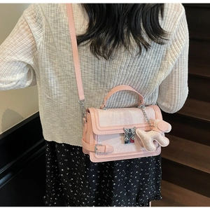 Detail of pink jacquard bag with floral relief and a cute plush dog pendant charm