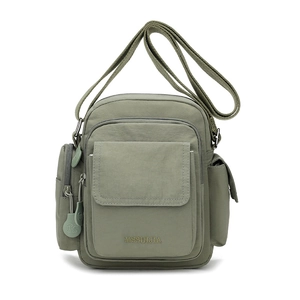 Detail view of the green nylon crossbody bag featuring multiple pockets and durable fabric