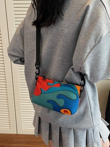Colorful abstract small crossbody bag with adjustable strap worn by model in gray outfit
