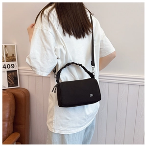 Detail of black nylon crossbody bag with ruffled handle and DD logo worn by a model