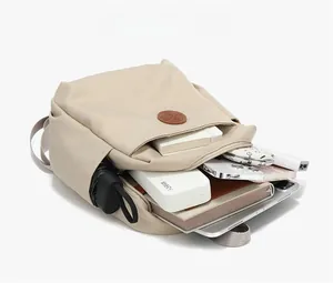 Detail view of beige nylon backpack interior with laptop, tablet, and travel essentials