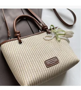 Detail of woven beach tote showing a leather logo tag and decorative floral tulip charm