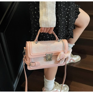 Detail of pink floral jacquard handbag with bow charm on a wooden staircase
