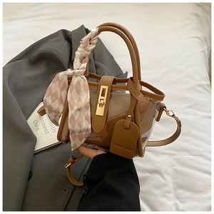 Detail view of transparent brown bucket bag with silk scarf and gold metal twist lock