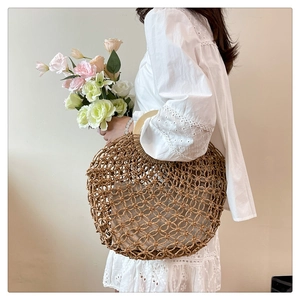 Detail of hollow woven straw handbag with round wooden handle and inner lining for beach