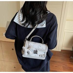 Detail of grey lace jacquard handbag with metal lock and cute rabbit charm
