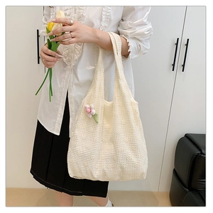 Detailed shot of beige lace tote bag with floral patterns and pink flower pendant