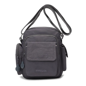Detail view of charcoal gray nylon crossbody bag showing multiple pockets and adjustable strap
