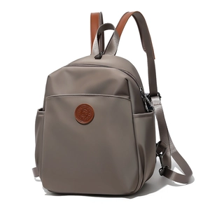 Detail of khaki nylon backpack featuring brown leather handles and fashion logo patch
