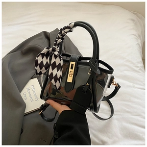 Detail of translucent black bucket bag with gold lock and checkered silk scarf handle