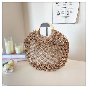 Detail of hollow woven straw handbag with round wooden handle and drawstring liner