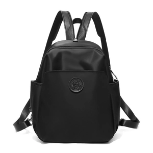 Detail of water-resistant black nylon backpack showing fashion logo badge and texture