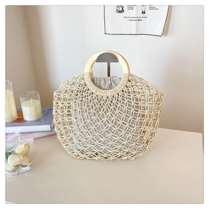 Detail of hollow woven handbag featuring round wooden handles and drawstring inner pouch