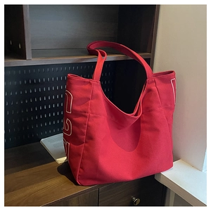 Macro shot of large red canvas tote bag with 1923 print on a dark wood background