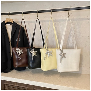 Detail of four woven bucket bags in brown, black, yellow, and white with star charms
