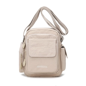 Detail view of beige nylon crossbody bag with multi-zipper pockets and embroidery