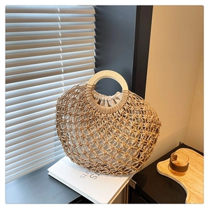 Detail of hollow woven straw handbag with wooden ring handles and drawstring liner