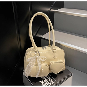 Close-up of a pale yellow patent leather bag with a heart pocket and lace pearl charm