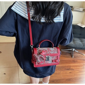 Macro shot of red leather handbag with vintage floral embroidery and bear charm detail