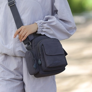 Detail of dark grey waterproof nylon crossbody bag with multi-pockets and wide strap