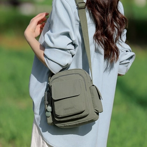 Detail of olive green nylon crossbody bag with wide shoulder strap and functional pockets