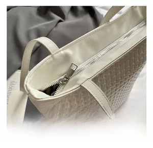 Detailed macro view of high-quality silver metal zipper and white woven texture on tote bag