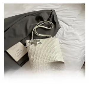 Close-up of white woven bucket bag with fine square texture and star charm