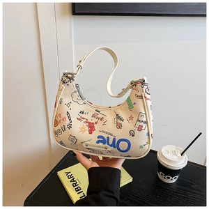 Detail view of beige canvas baguette bag with colorful graffiti and adjustable leather strap