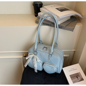 Detailed close-up of light blue glossy handbag with heart pocket and pearl bow charm