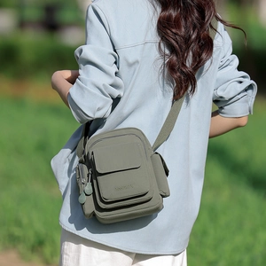 Detailed close-up of the multi-pocket nylon crossbody bag with embossed brand logo