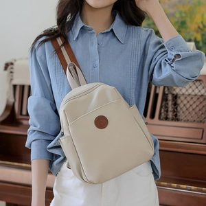 Close-up of beige waterproof backpack with brown adjustable strap and round leather patch