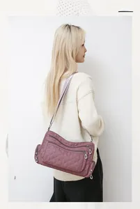 Detail view of purple quilted nylon shoulder bag showing multiple zipper compartments