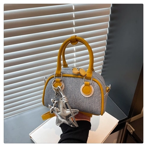 Close-up of denim mini bag featuring yellow leather trim and a silver star charm