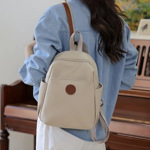 Close-up of beige nylon backpack with fashion leather patch in a cozy indoor setting