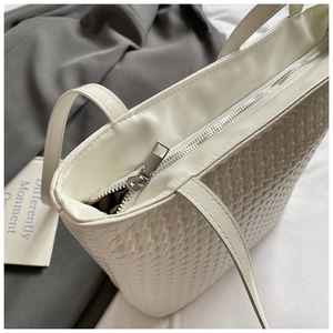 Close-up of white woven leather bucket bag featuring a secure silver metal zipper closure