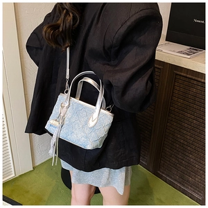 Detail of light blue pleated handbag with silver strap and tassel on a female model