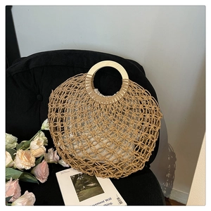Detail of woven beach tote with natural straw mesh and round wooden handle detail