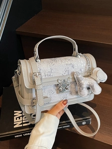 Gray jacquard handbag with floral pattern, bird buckle and dog charm on wooden steps