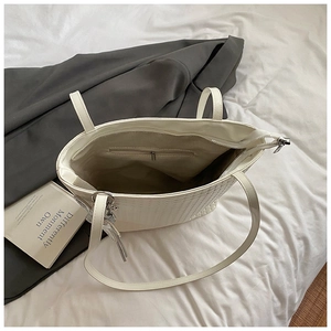 Detailed top view of a white woven texture tote bag with silver zipper closure and interior pocket