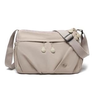 Close-up of beige nylon crossbody bag with multi-zipper pockets and adjustable strap