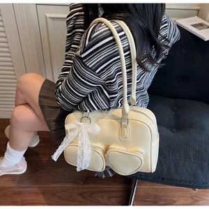 Detail of cream Boston bag featuring a unique heart-shaped pocket and lace bow charm