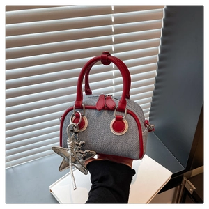 Dettaglio ravvicinato di una mini borsa Boston in denim blu con finiture in pelle rossa