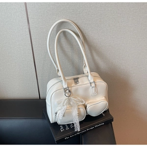 Close-up of cream white glossy leather shoulder bag with pearl lace heart charm and zip pockets