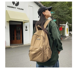 Khaki canvas backpack detail showing side view with front pocket and durable texture