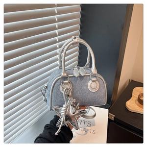 Detail of denim Boston bag with silver star charm and metallic leather trim detailing
