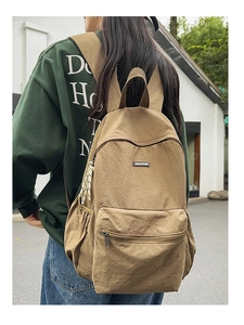 Outdoor shot of khaki canvas backpack with zipper pockets and logo on street