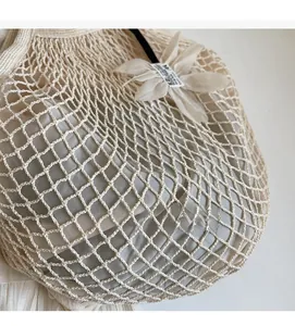 Detail of cream woven mesh tote bag showing intricate knit texture and floral accent